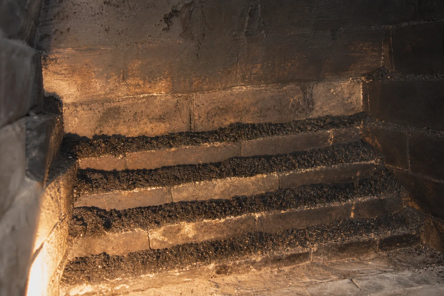 Smoke chamber repair, before: stair-stepped corbeled brick with creosote collected on every exposed mortar ledge