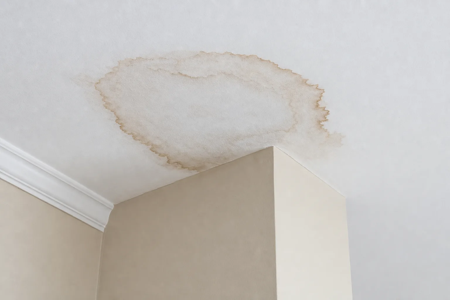 Flashing around chimney failure shown as a brown water stain on a bedroom ceiling