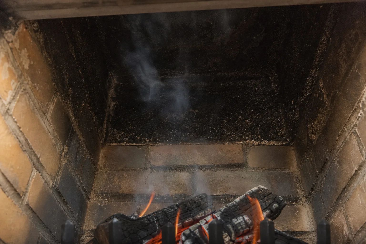 Creosote residue coating a cool masonry flue above a burning wood fireplace