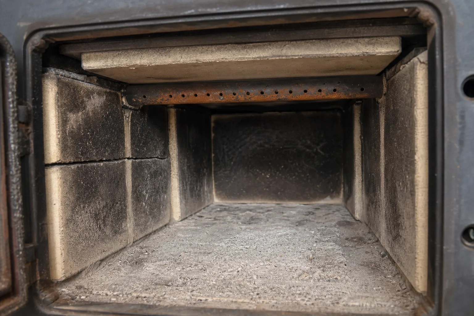 Wood stove repair inspection: firebox interior with cracked firebrick, refractory baffle and secondary air tubes