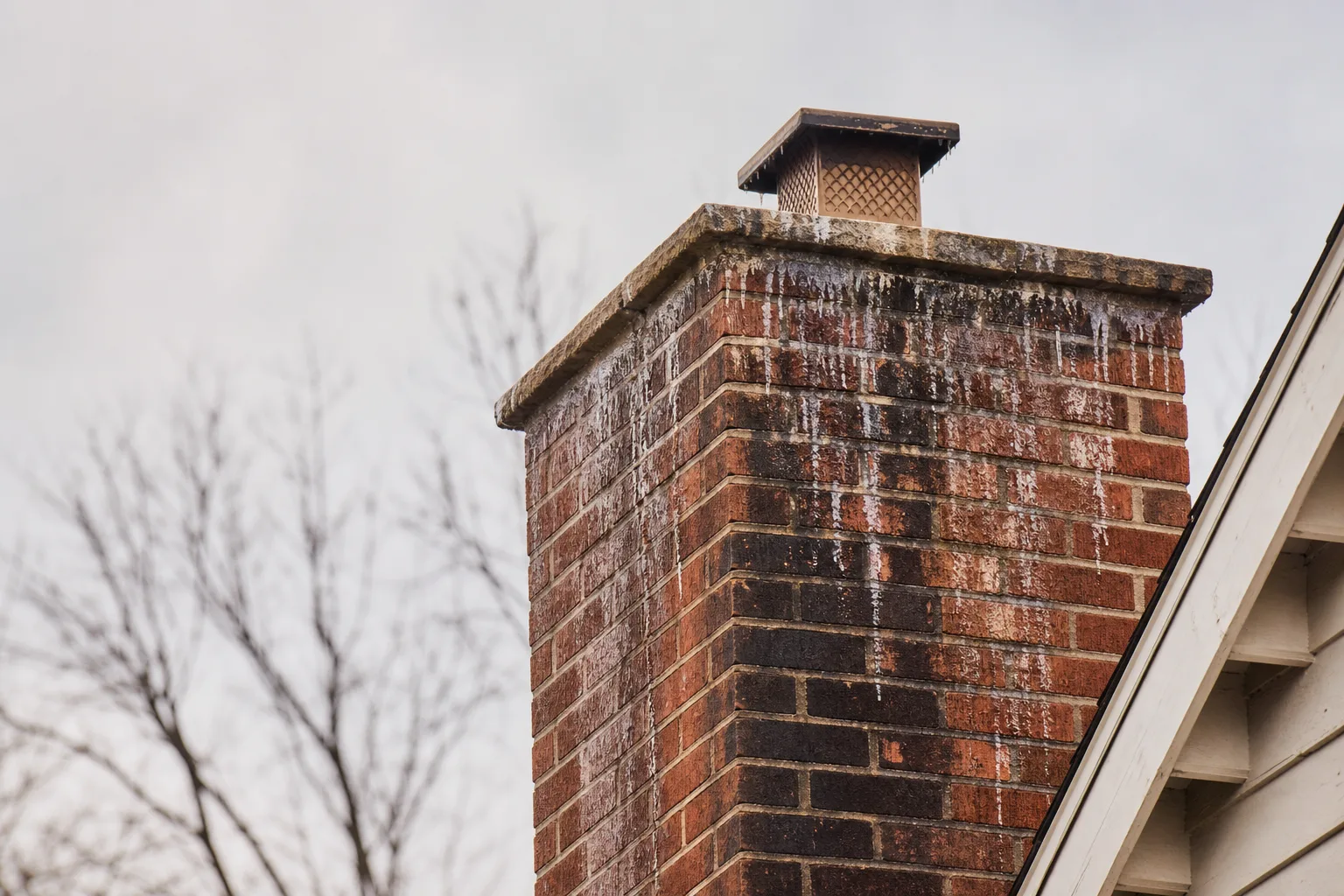 Masonry work damage from freeze-thaw cycling visible on a frosted brick chimney in winter