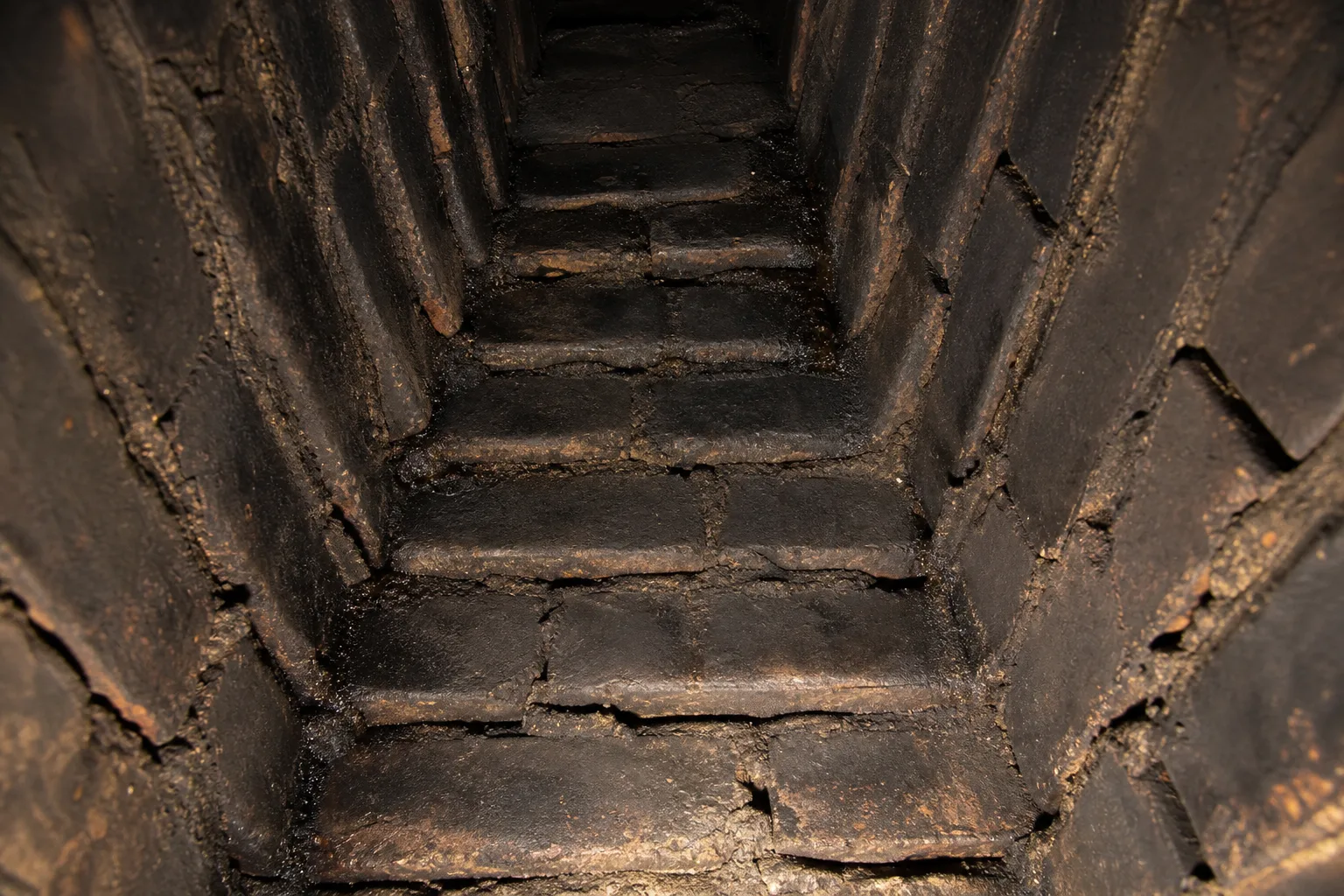 Smoke chamber parging before condition, a stair-stepped corbeled smoke chamber caked with soot