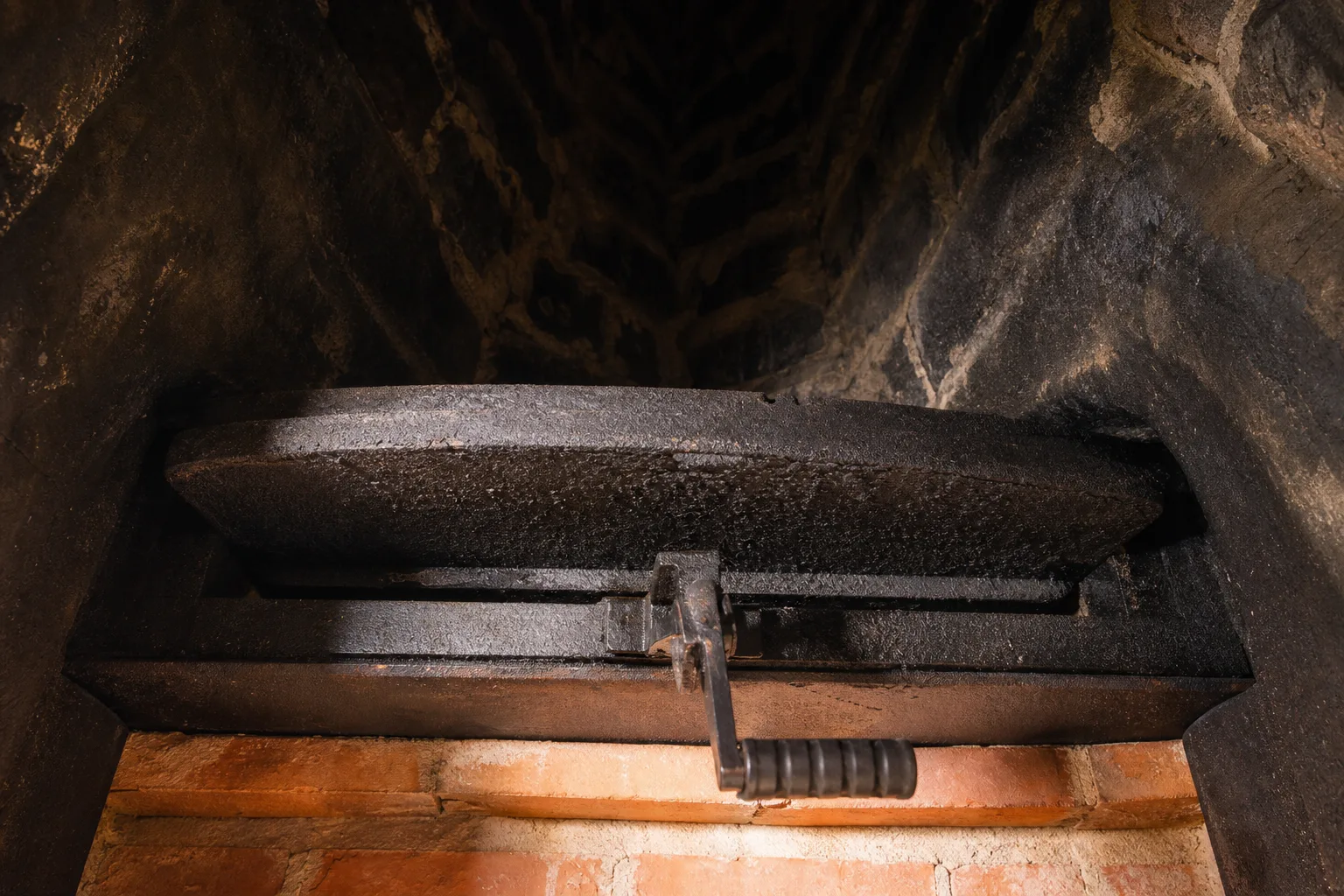 Chimney parts in the transition zone: a cast iron throat damper seen from below the fireplace