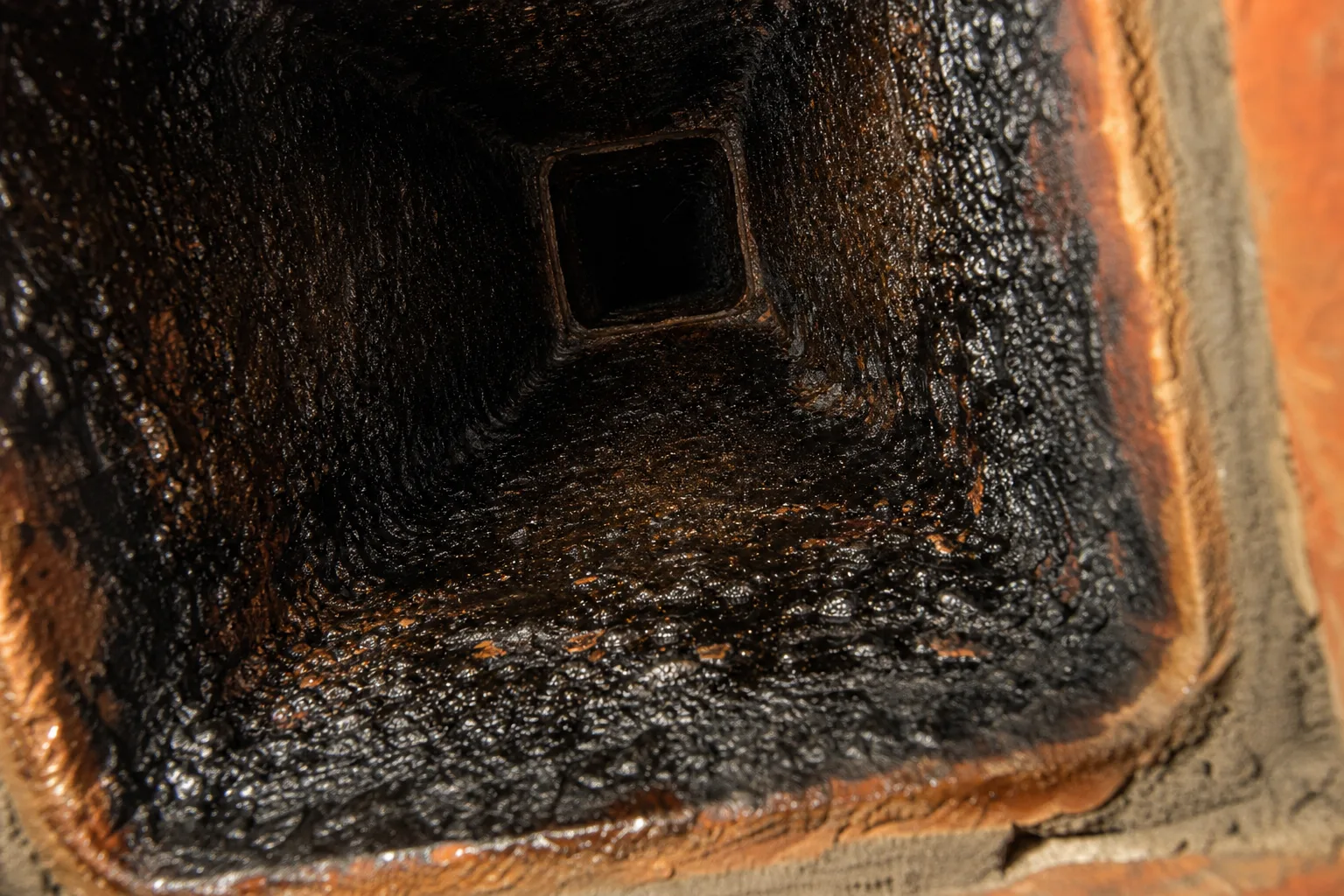 how often should you clean your chimney: glazed creosote coating the inside of a clay flue tile