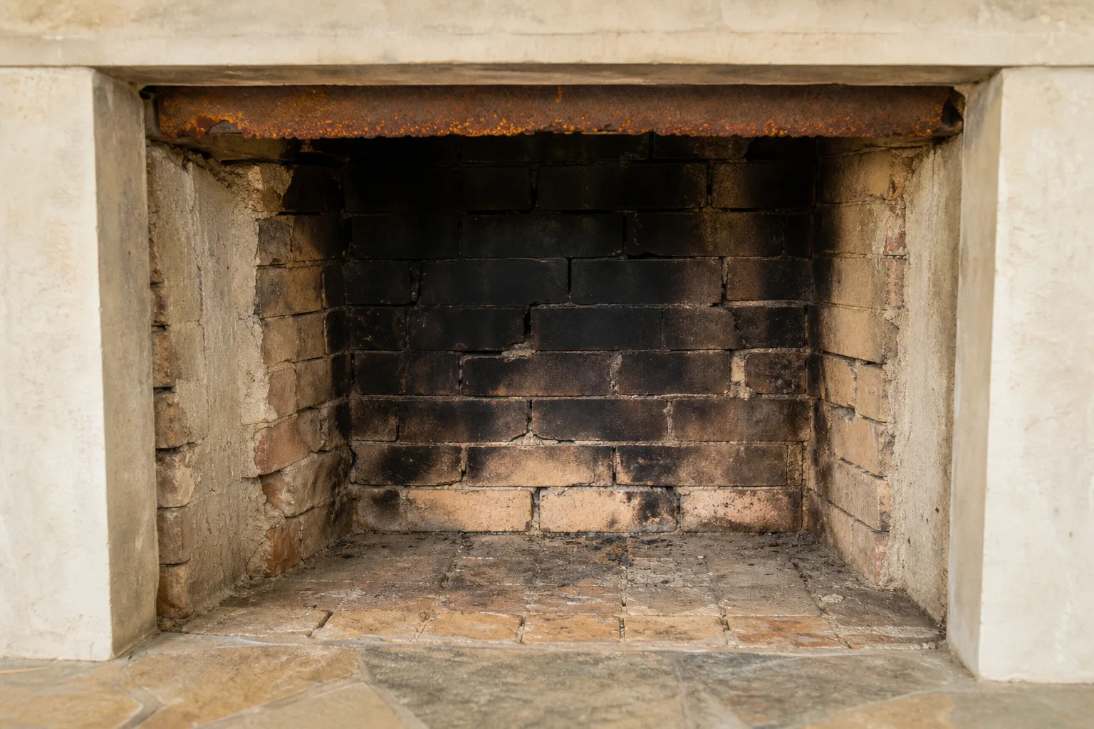 convert gas fireplace to wood: a masonry firebox in typical worn condition with spalled firebrick and a rusted damper plate