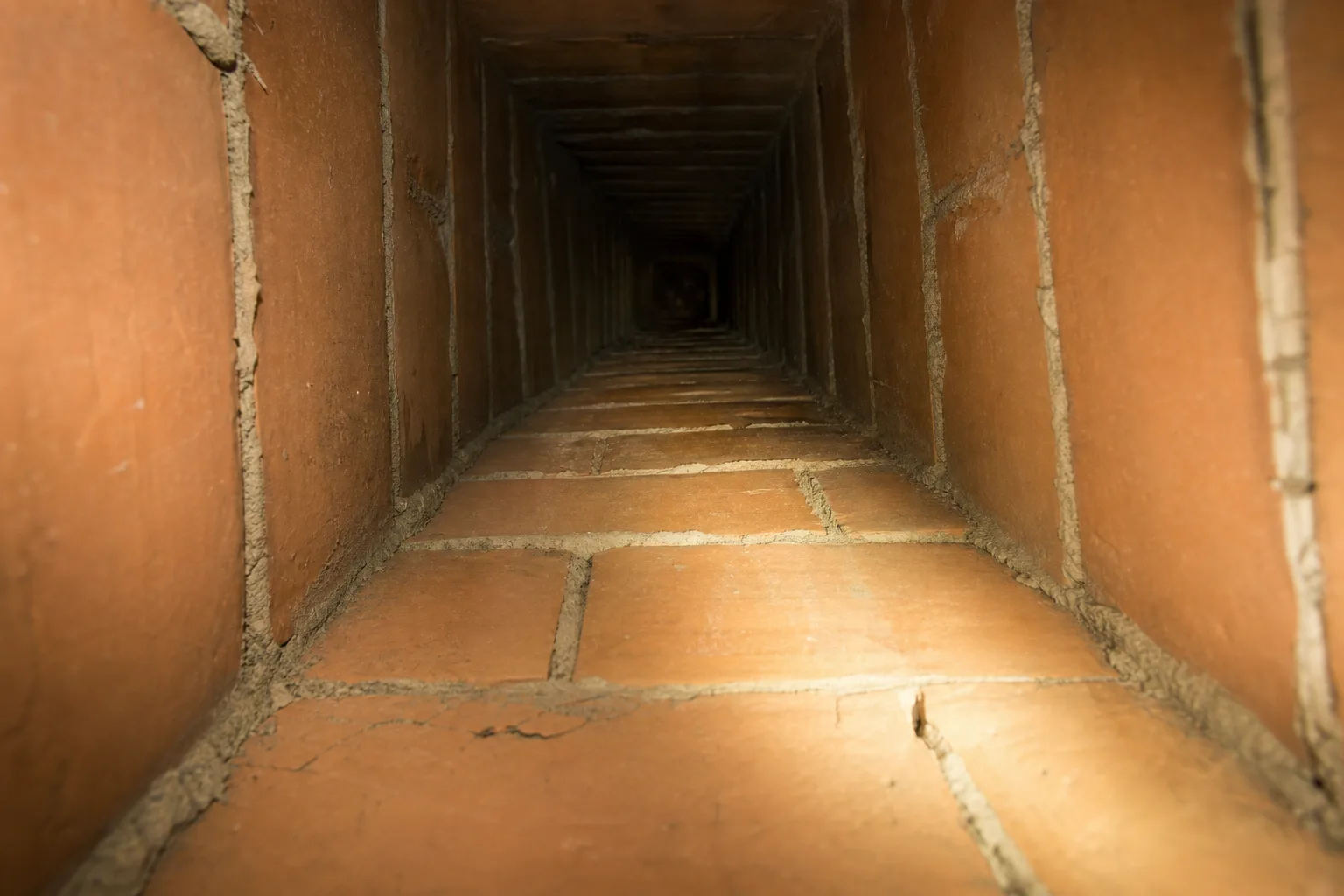 How to clean a chimney: looking up a clay tile masonry flue with a flashlight