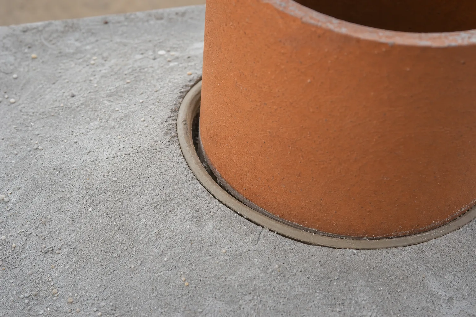 concrete chimney crown detail showing the expansion joint and sealant line around the clay flue tile