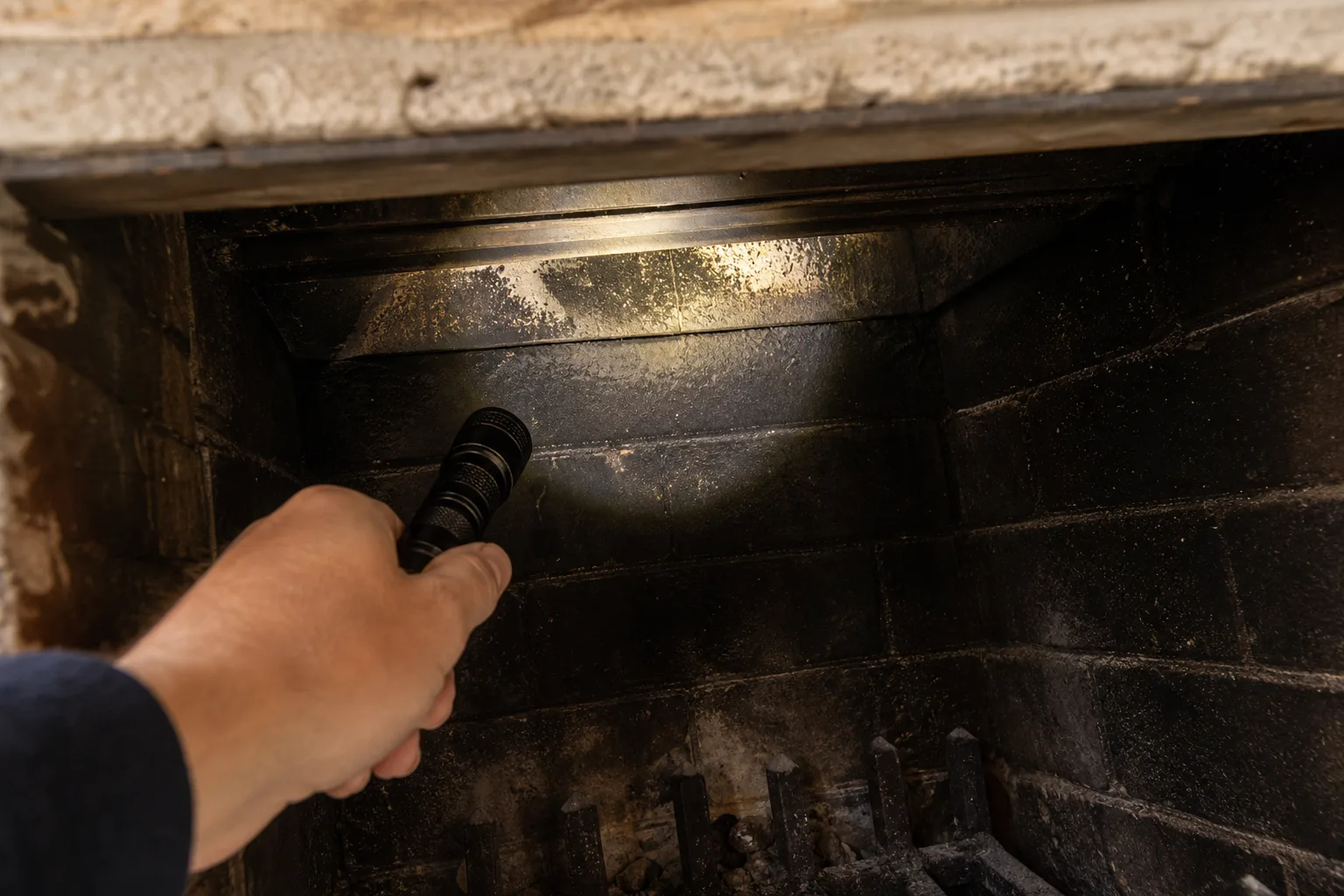 Fireplace damper replacement check: a flashlight aimed up into the firebox throat