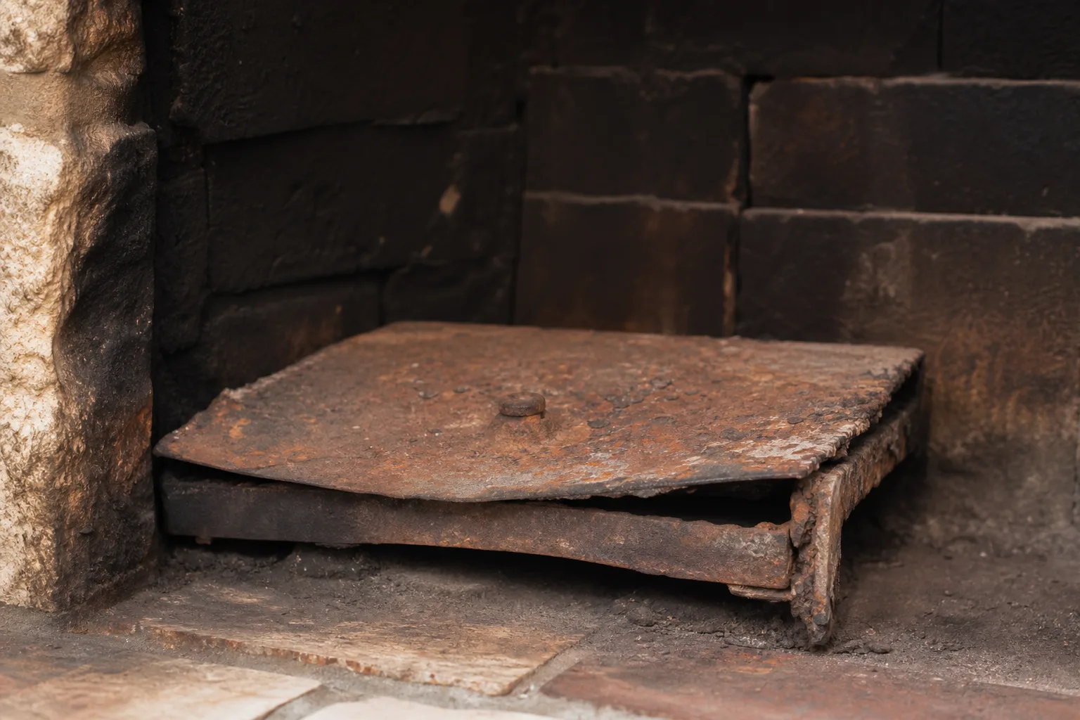 Chimney damper in worn typical condition, with a rusted warped plate that no longer seats flat