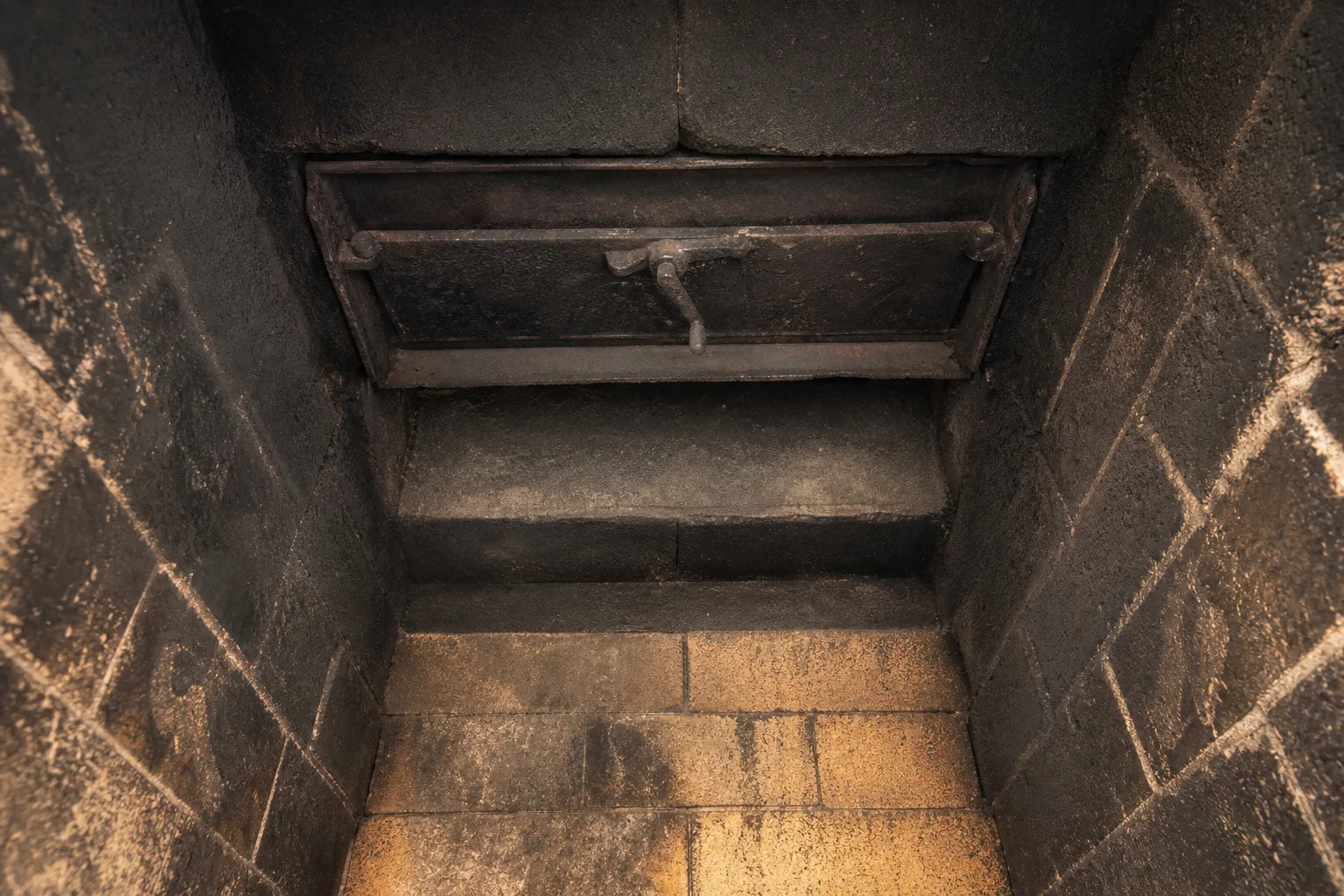 Chimney damper seen from inside the firebox, with the smoke shelf behind it