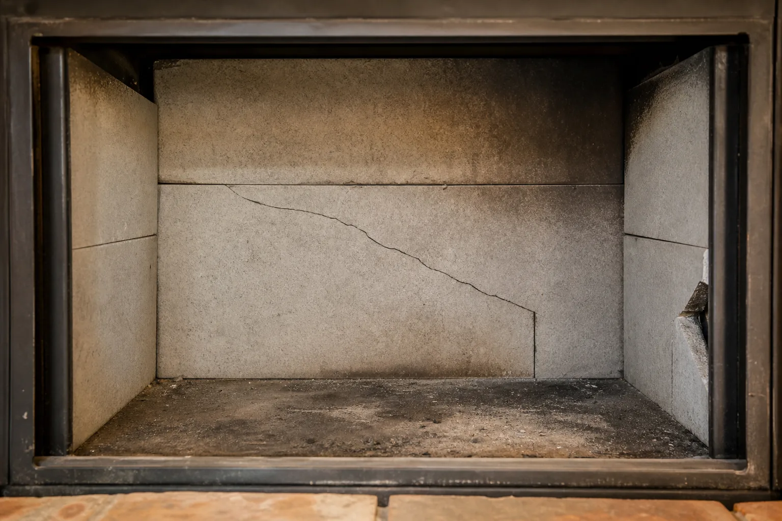 Fireplace repair cost for prefab units hinges on cracked refractory panels like this one