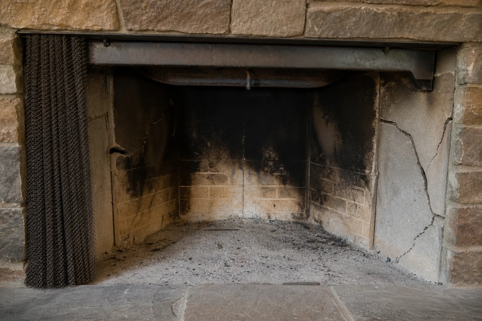 Convert wood fireplace to gas: a sooty wood-burning firebox with cracked refractory panels in typical condition before the work begins