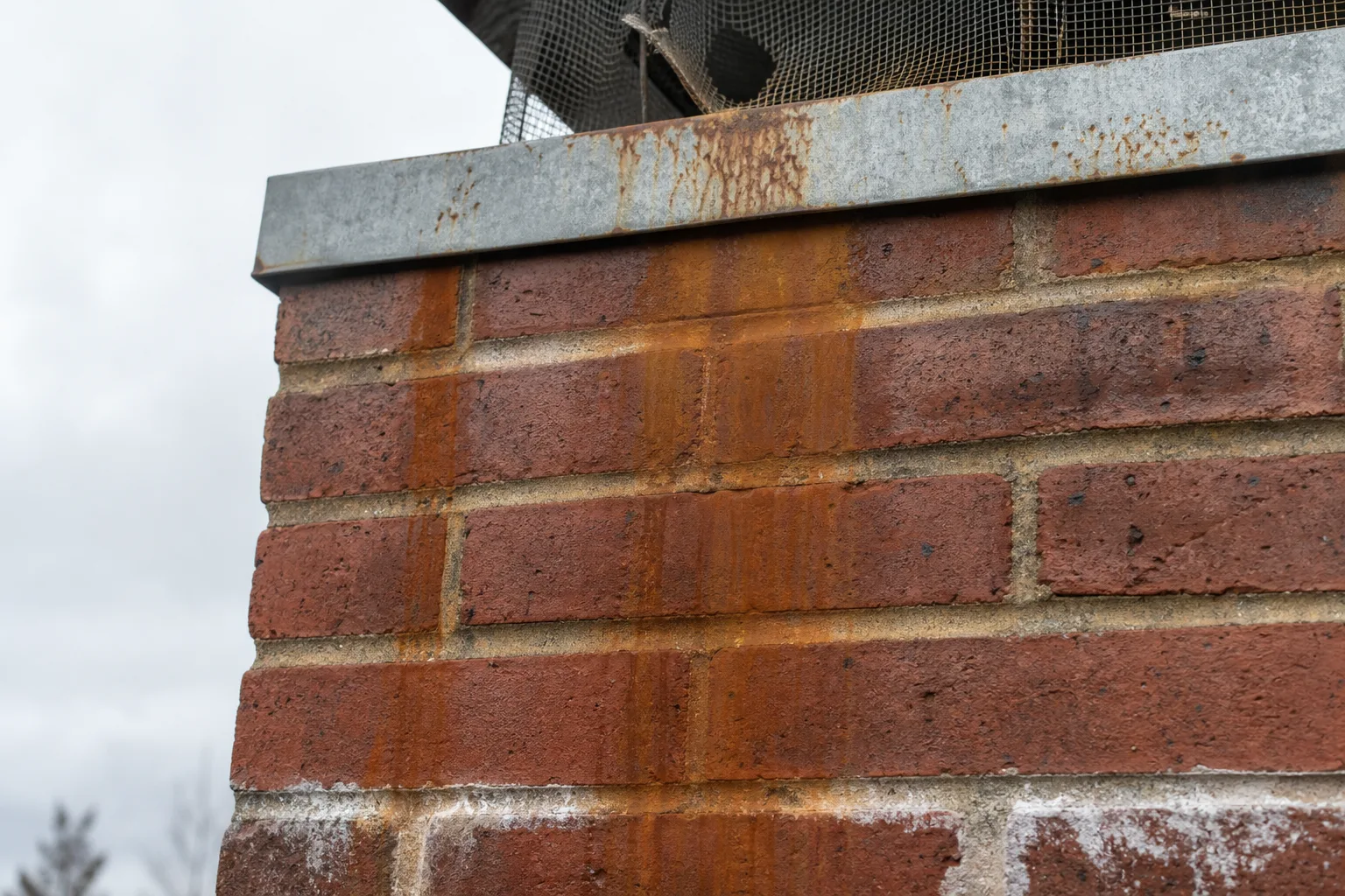 Chimney repair CT: rust streaks running down brick from a failing steel chimney cap