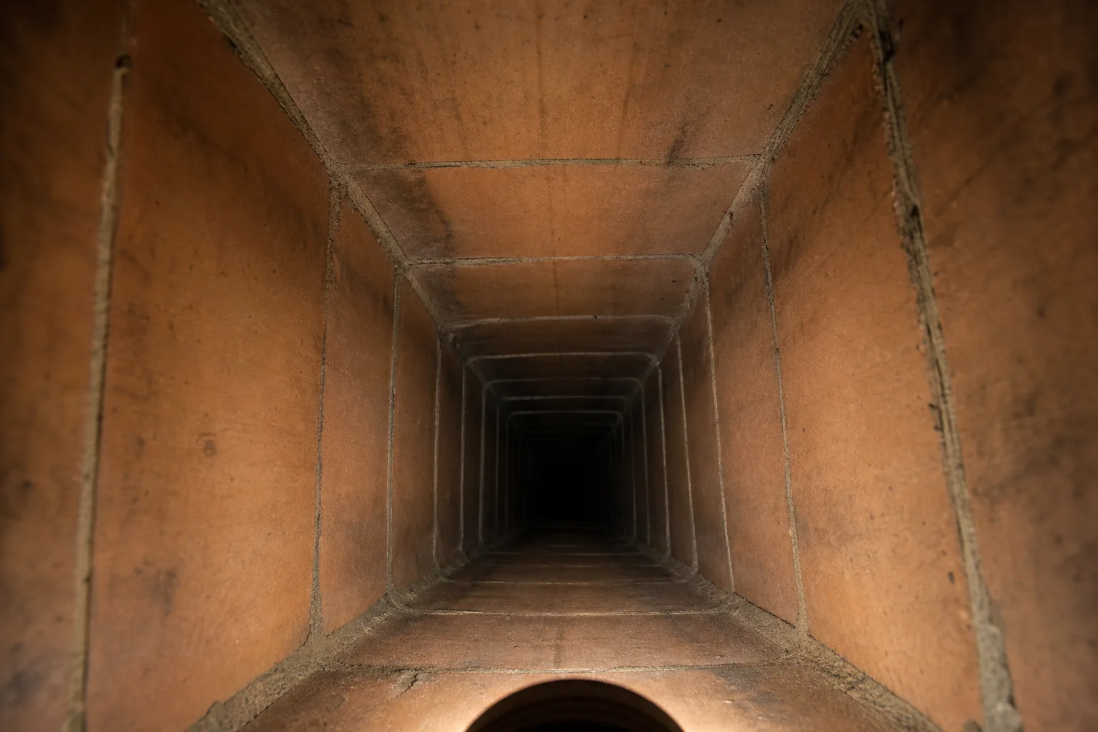 Swept flue showing bare clay tile liner and visible joints with only faint soot staining