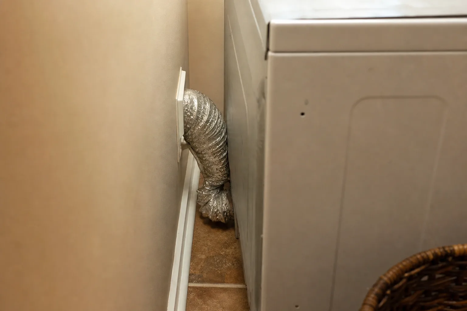Crushed silver foil dryer hose kinked tightly behind a clothes dryer Crushed silver foil dryer hose kinked tightly behind a clothes dryer