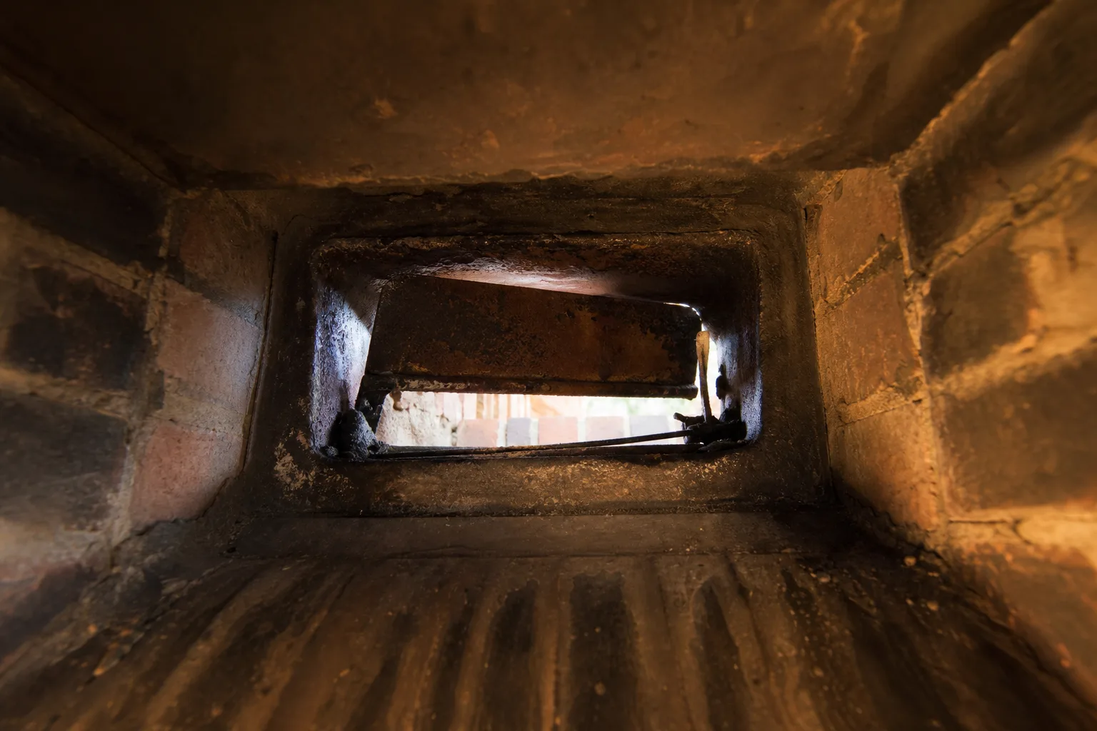 Rusted throat damper plate seized part-open, seen by torchlight from the firebox Rusted throat damper plate seized part-open, seen by torchlight from the firebox
